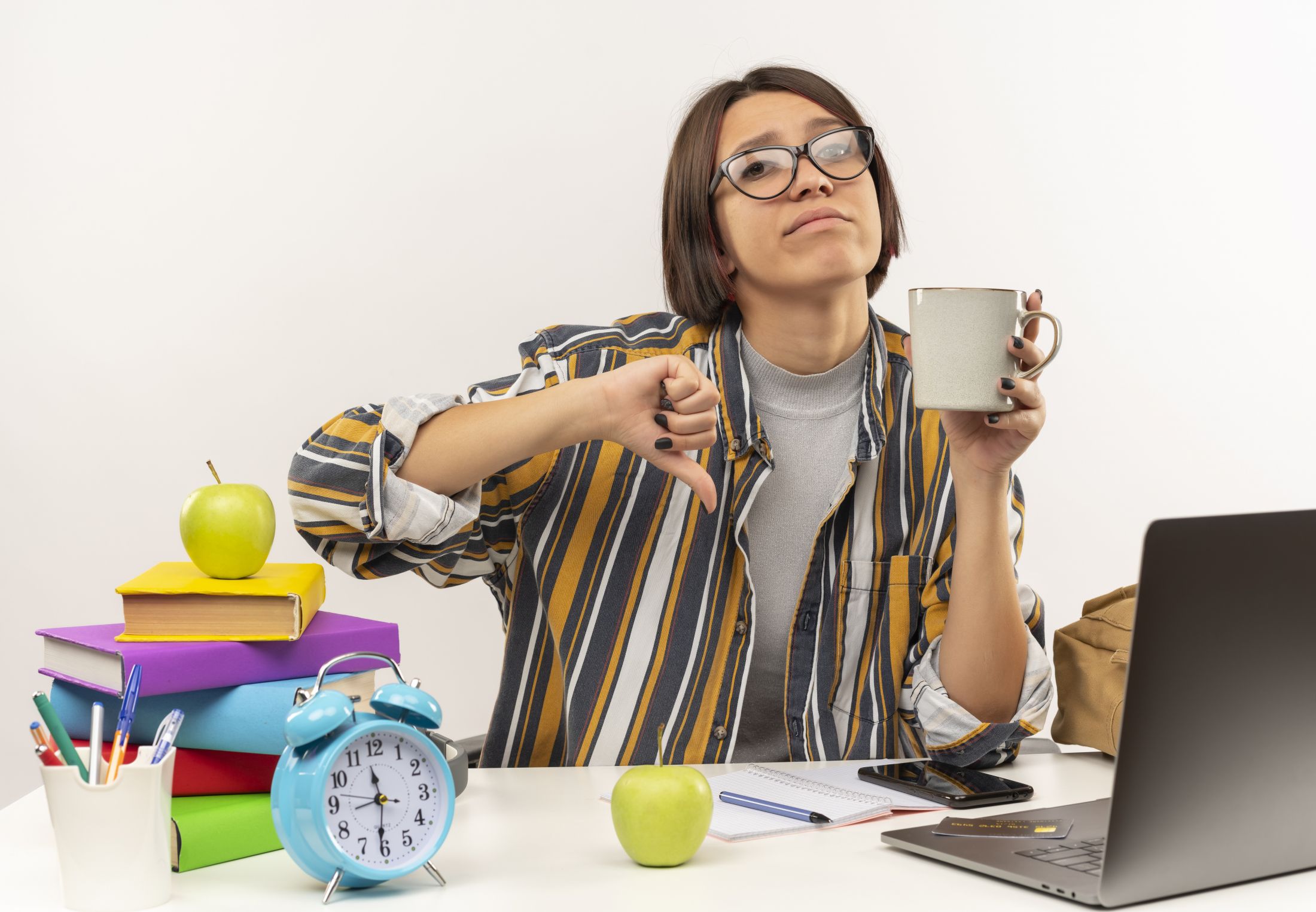 unpleased-young-student-girl-wearing-glasses-sitting-desk-with-university-tools-holding-cup-coffee-showing-thumb-down-isolated-white-background.jpg