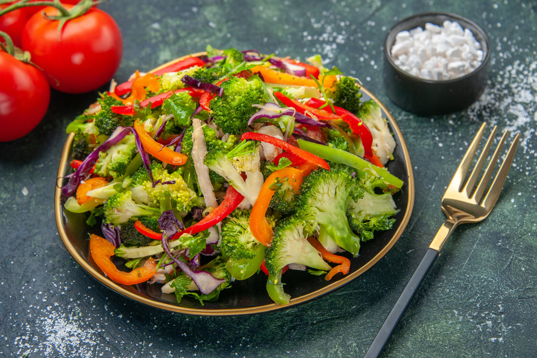 side-view-vegan-salad-plate-with-various-vegetables-fork-tomatoes-with-stem-dark-background.jpg