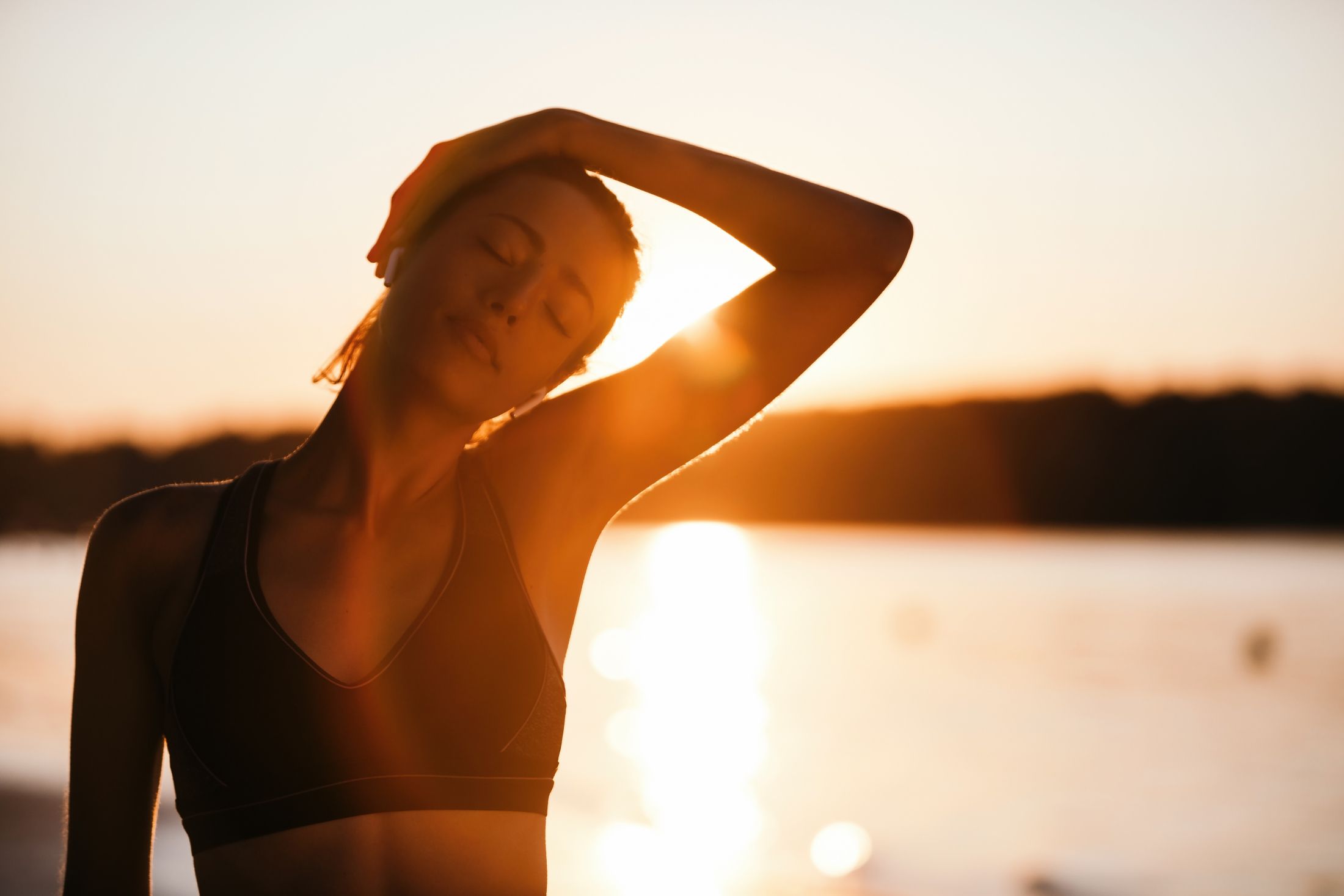 young-athletic-woman-stretching-her-neck-while-exercising-at-sunrise-at-riverside.jpg