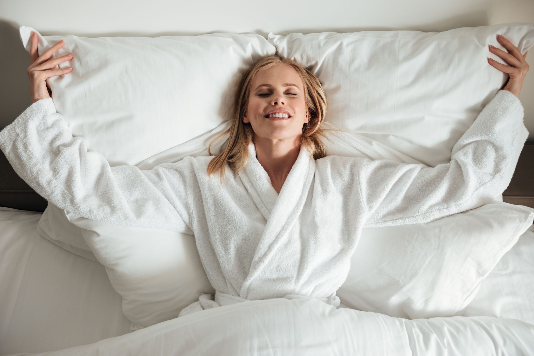 young-happy-woman-lying-on-big-white-bed.jpg