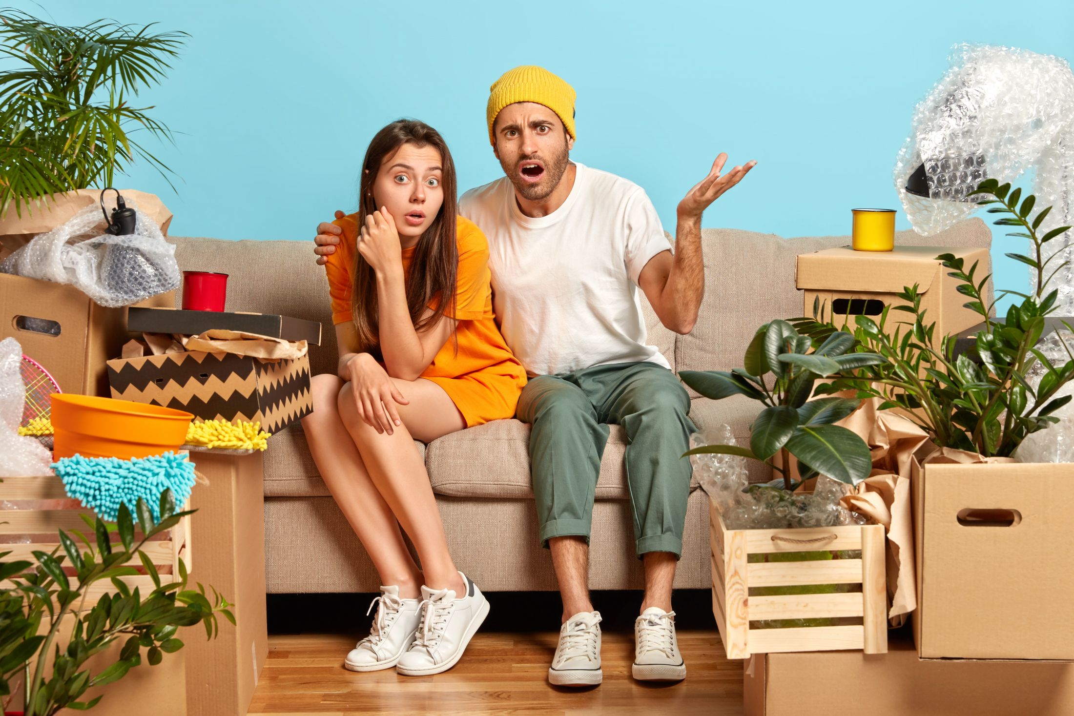 woman-and-man-tenants-pose-at-cozy-sofa-in-empty-messy-room-with-different-household-things-frustrated-guy-looks-with-great-puzzlement-embraces-girlfriend-couple-moves-in-new-flat-for-living.jpg