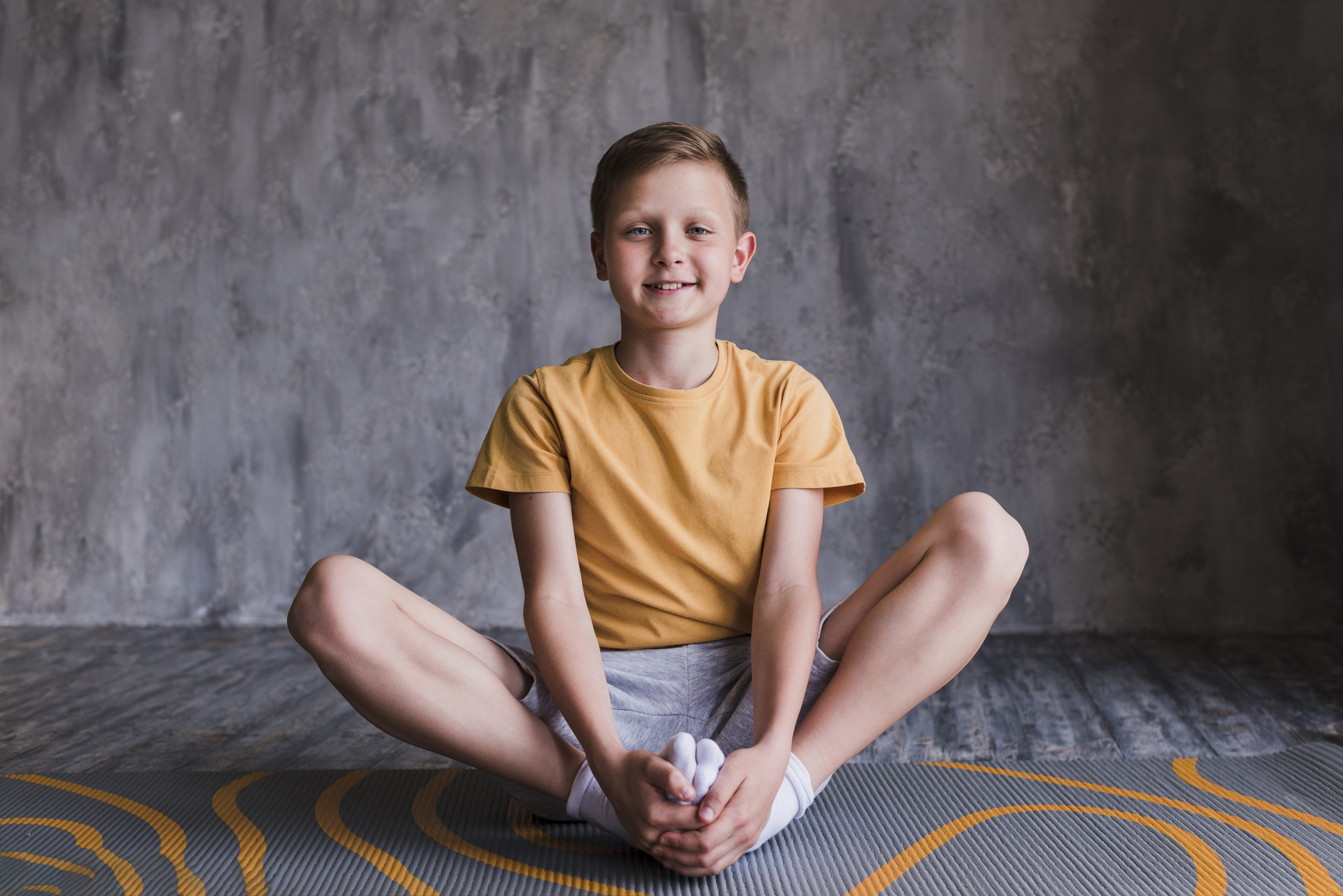 portrait-smiling-boy-sitting-exercise-mat-looking-camera.jpg
