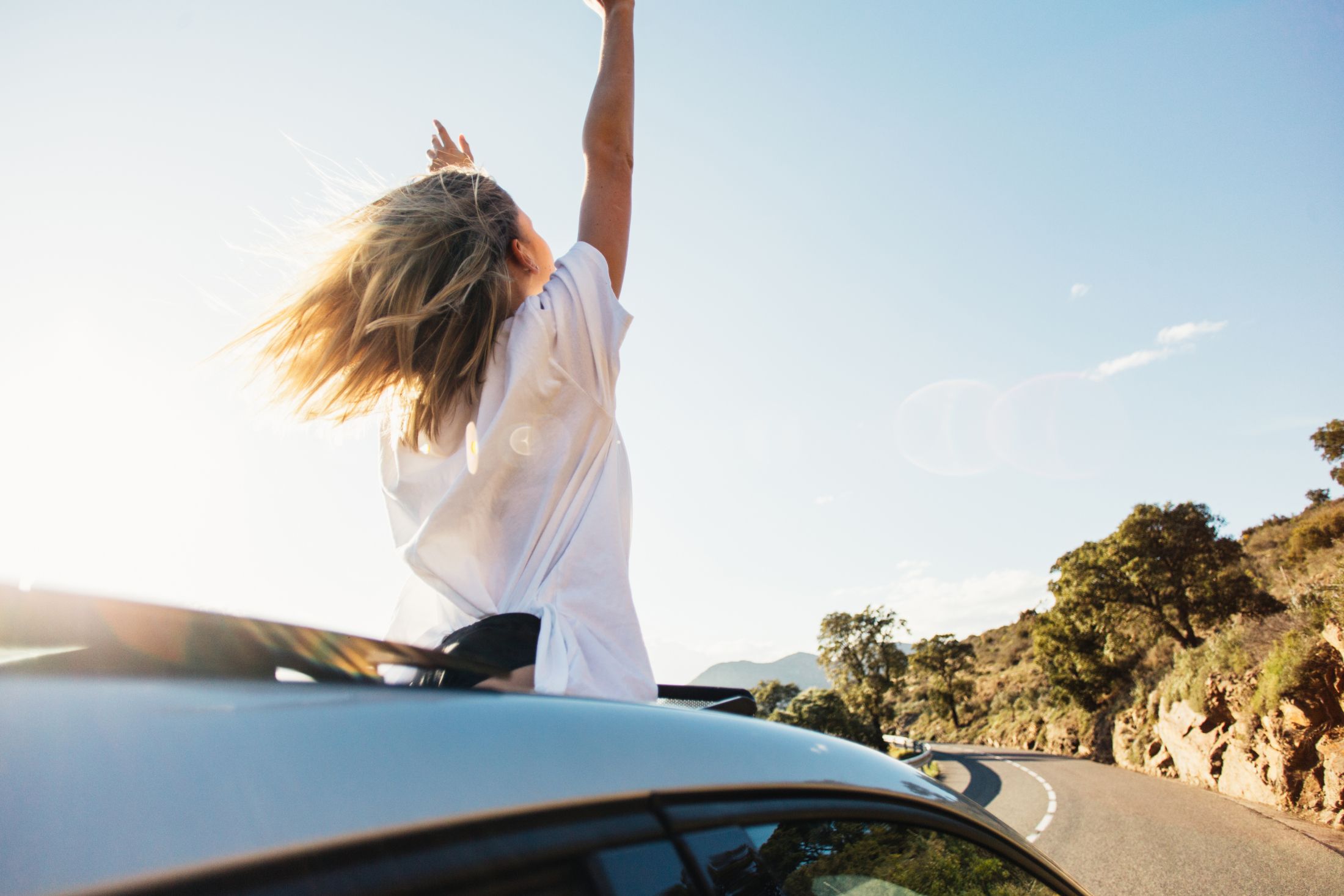 woman-in-car-road-trip-waving-out-the-window-smiling.jpg