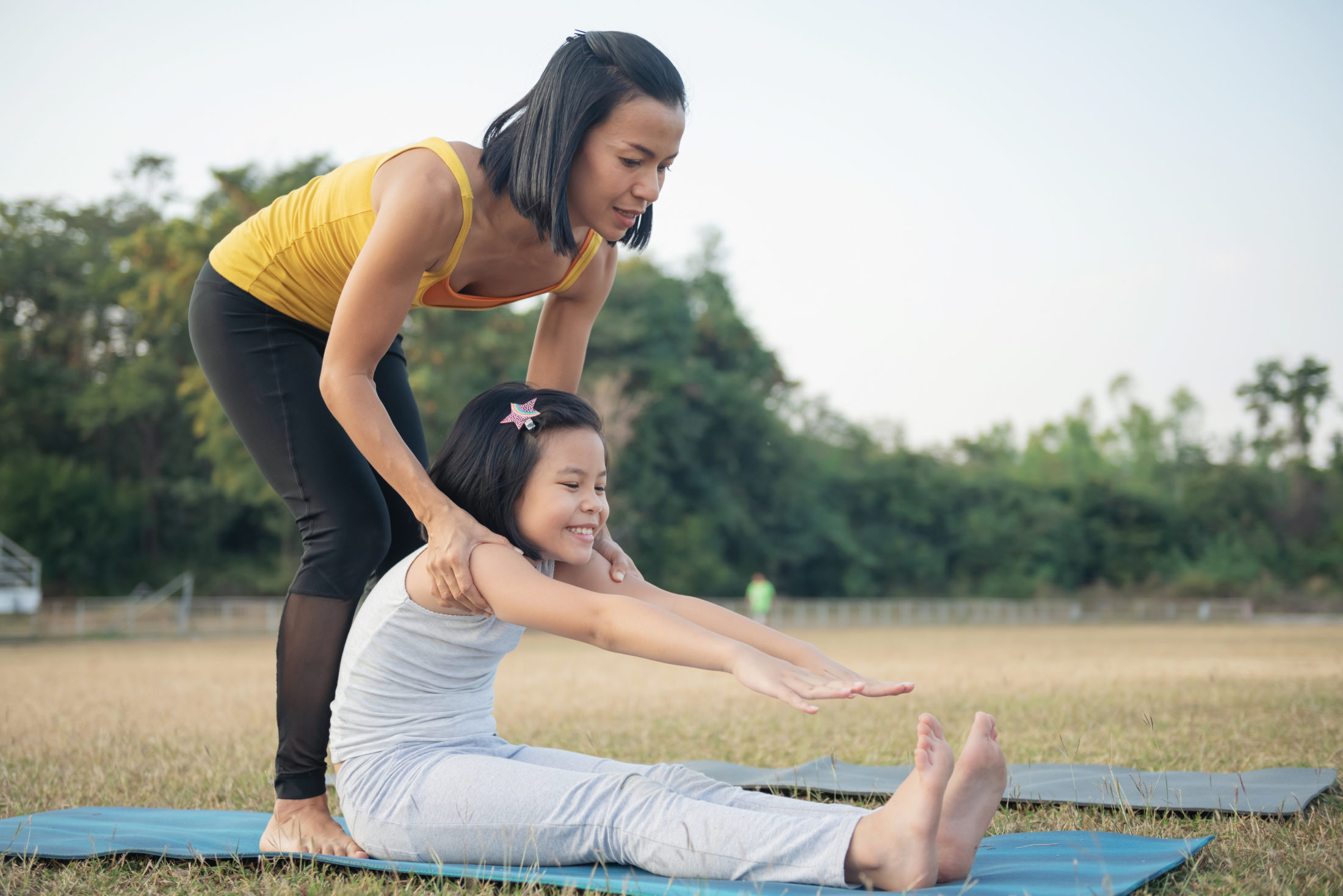mother-and-daughter-doing-yoga-woman-and-child-training-in-the-park-outdoor-sports-healthy-sport-lifestyle-sitting-in-paschimottanasana-exercise-seated-forward-bend-pose.jpg