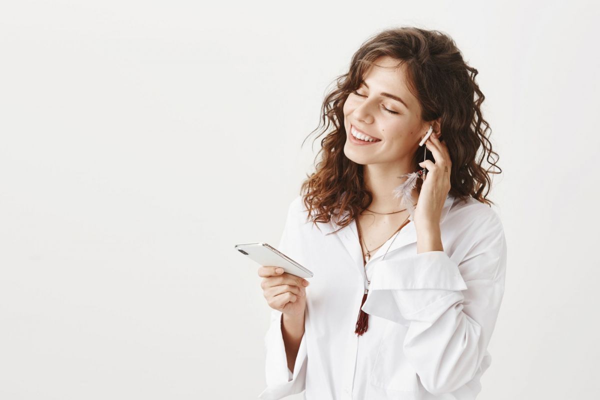 attractive-stylish-woman-listening-music-in-wireless-earphones-holding-smartphone.jpg