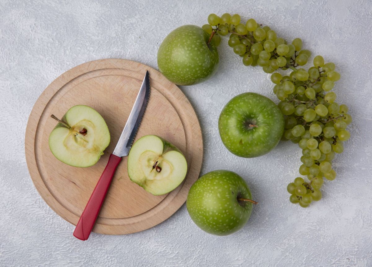 top-view-green-apple-slices-with-a-knife-on-a-stand-with-green-grapes-on-a-white-background.jpg