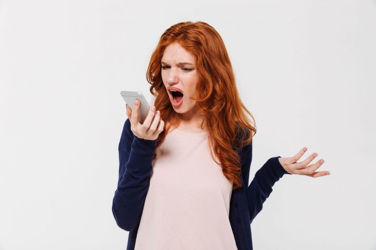 angry-young-redhead-lady-talking-by-mobile-phone-and-screaming.jpg