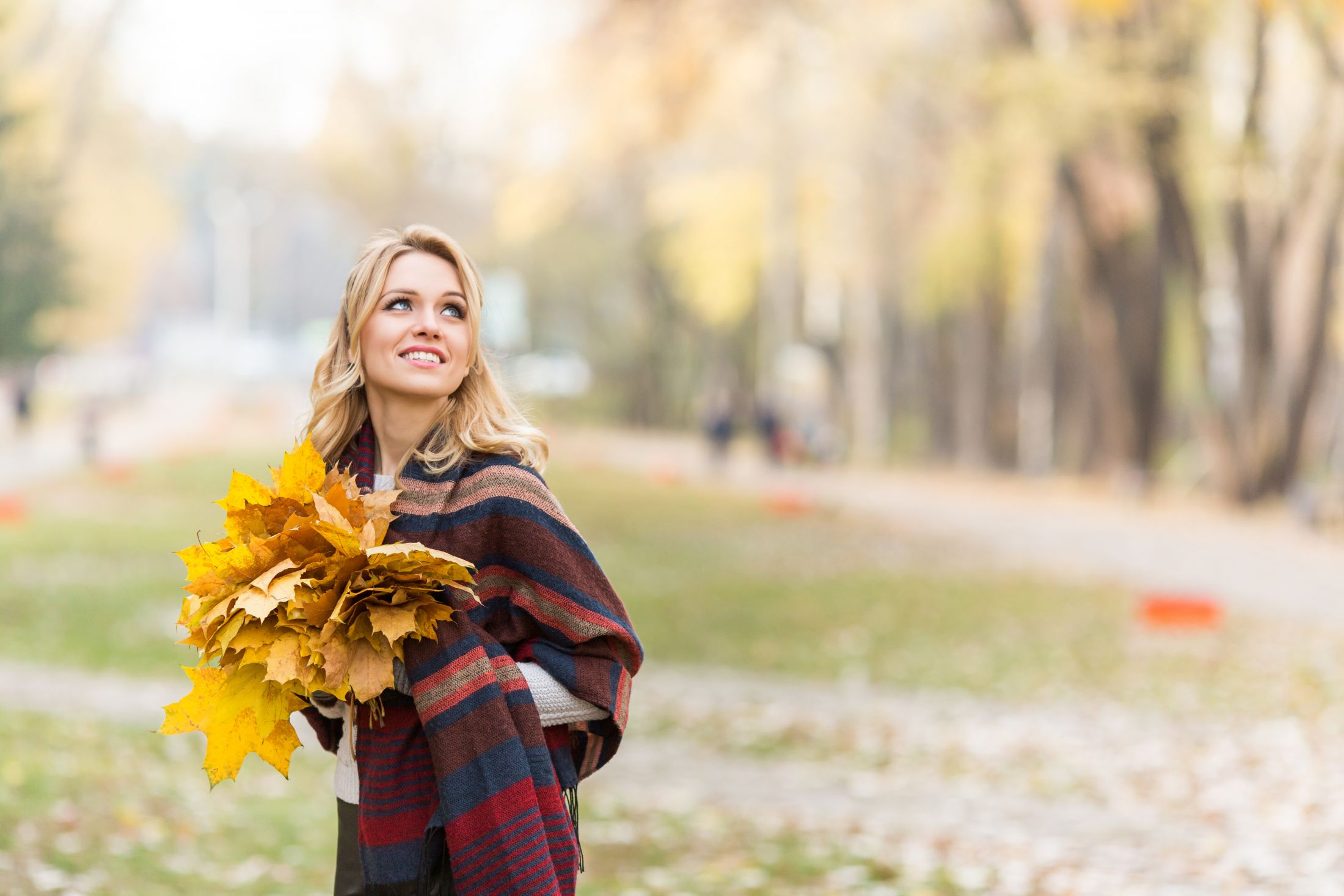 cheerful-blond-woman-walking-in-the-autumn-park-with-a-bouquet-from-maple-leaves.jpg