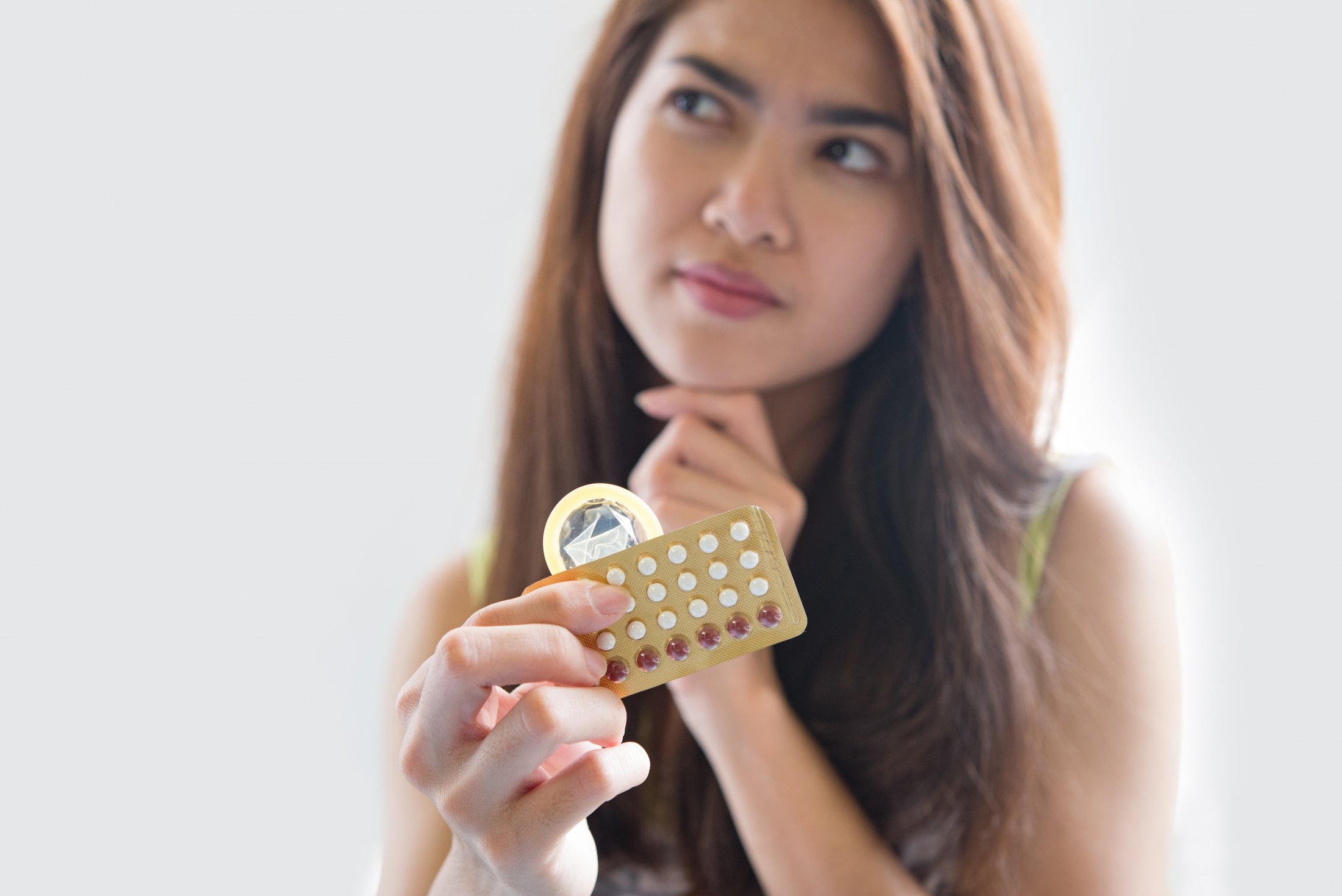 young-woman-holding-condom-and-contraceptive-pills-prevent-pregnancy.jpg