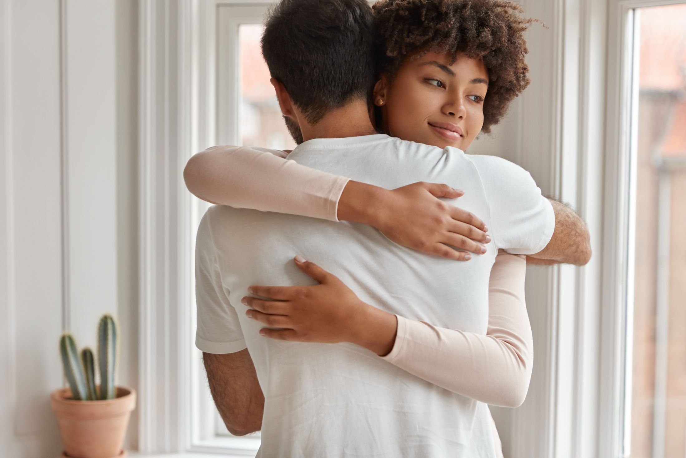 happy-mixed-race-couple-embrace-each-other-express-support-and-love-have-friendly-relationships-pose-near-window-in-living-room-enjoy-togetherness-diverse-boyfriend-and-girlfriend-hug-indoor.jpg