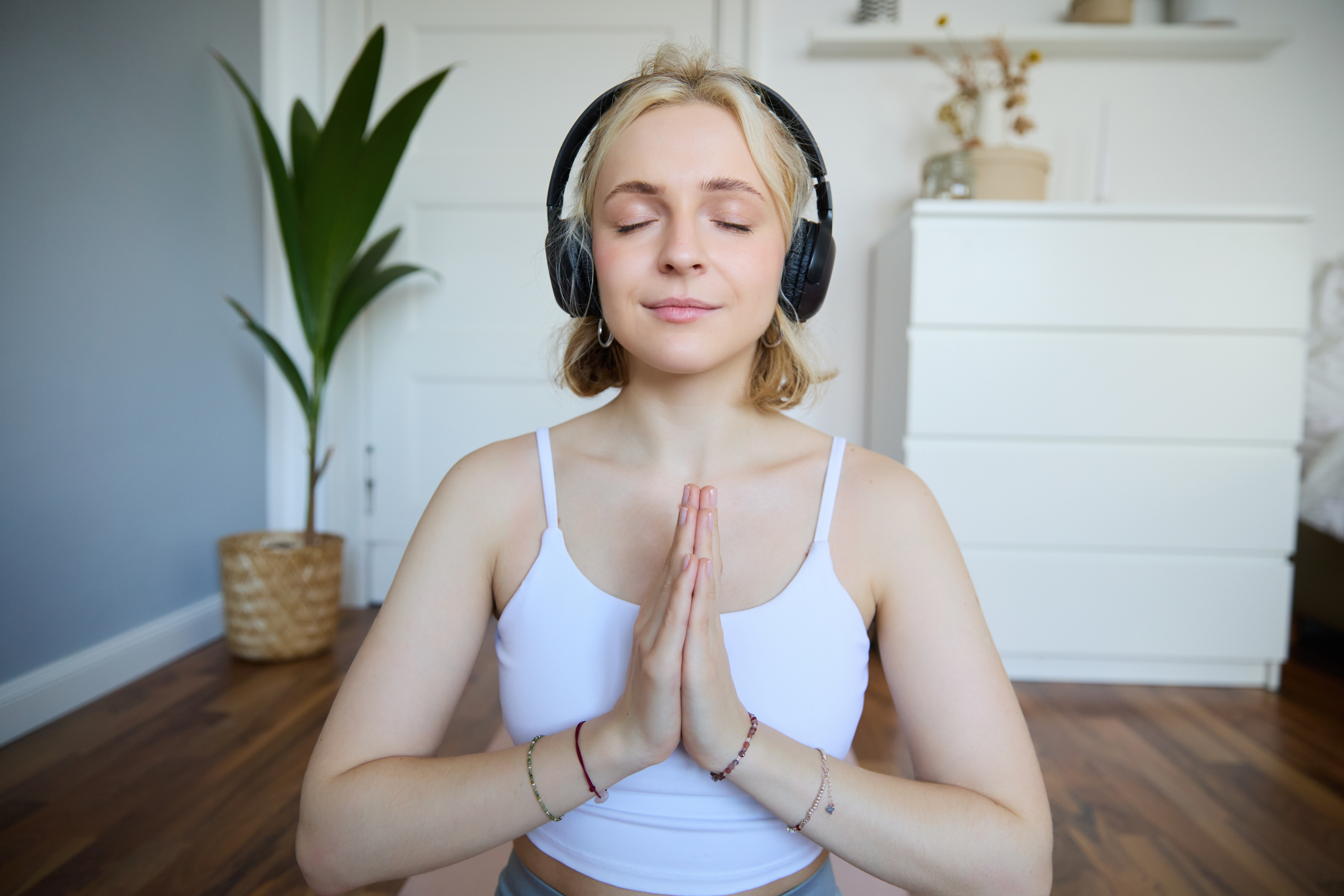 portrait-woman-meditating-home-sitting-headphones-listening-yoga-podcast-holding-hands.jpg